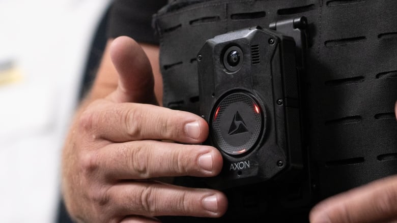 A man's fingers press a black device strapped to his torso. The device is lit red.