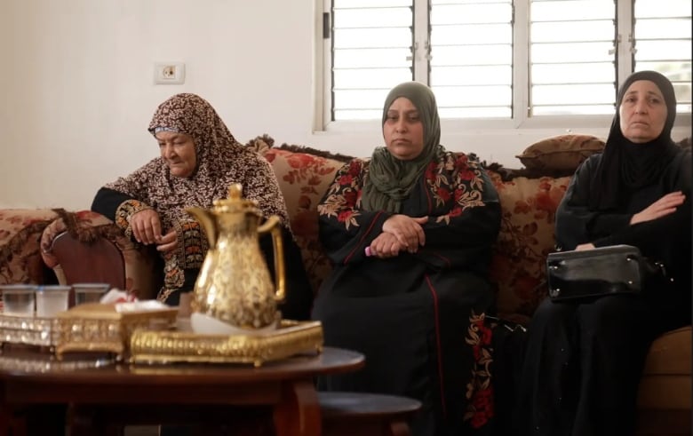 Three people are seen seated on a couch.