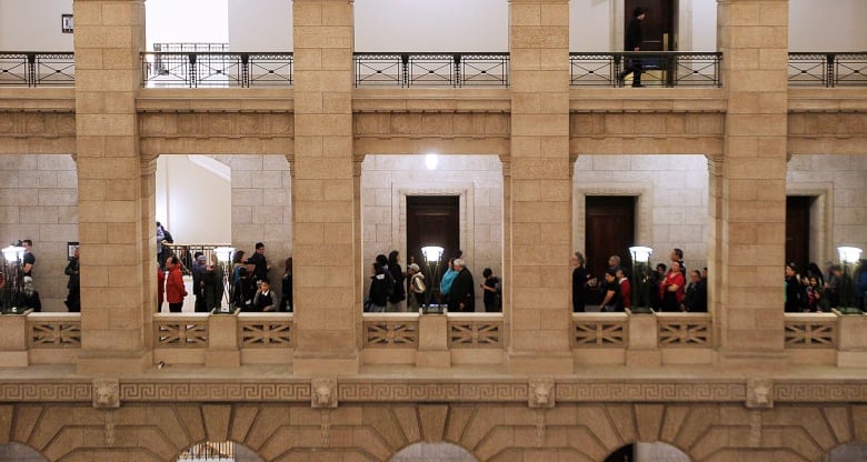 People line up along a hallway of an elaborate stone building