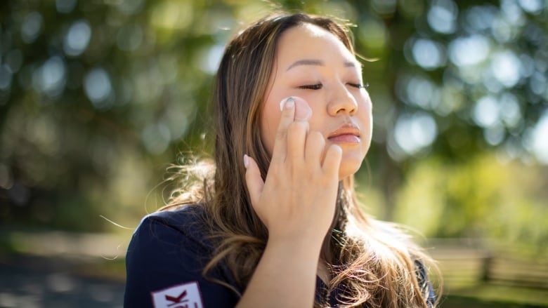 A person applies sunscreen to their face.