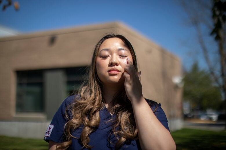 A person applies sunscreen to their face.