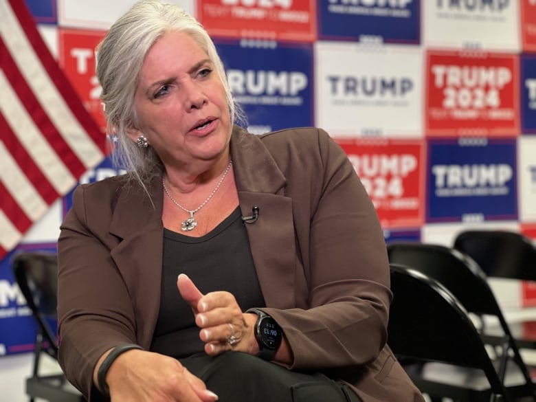 Woman seated in front of Trump signs