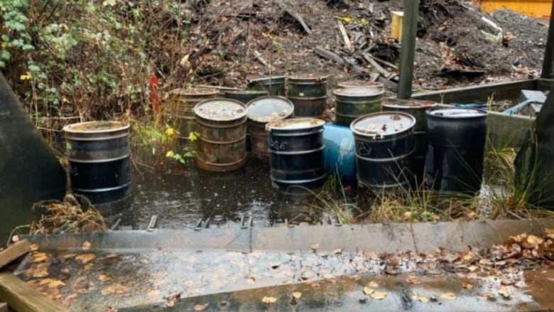 unlabeled drums site in front of a mound of earth