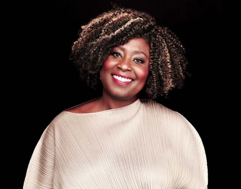 A smiling Black woman wearing a white shirt.