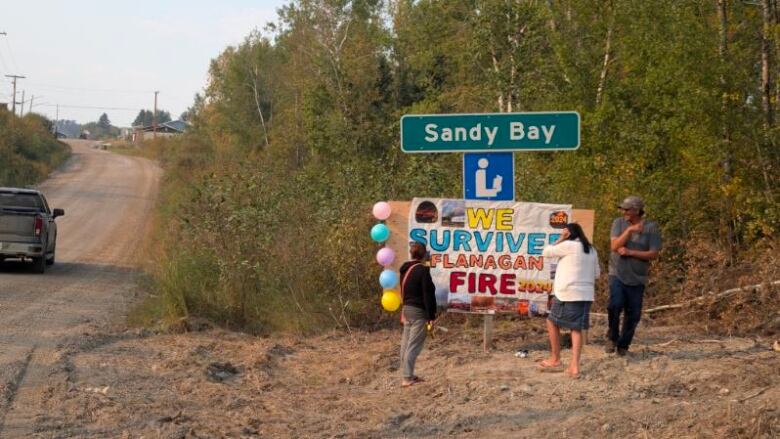 people stand by a homemade sign that reads 