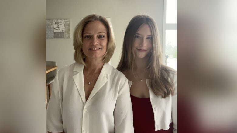 A mother and her daughter are pictured similing in their living room.