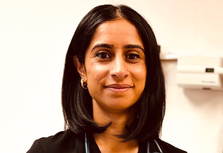 A woman stands with a stethoscope. 