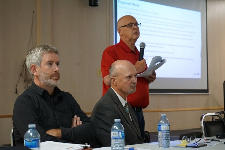 Three men looking at a crowd.