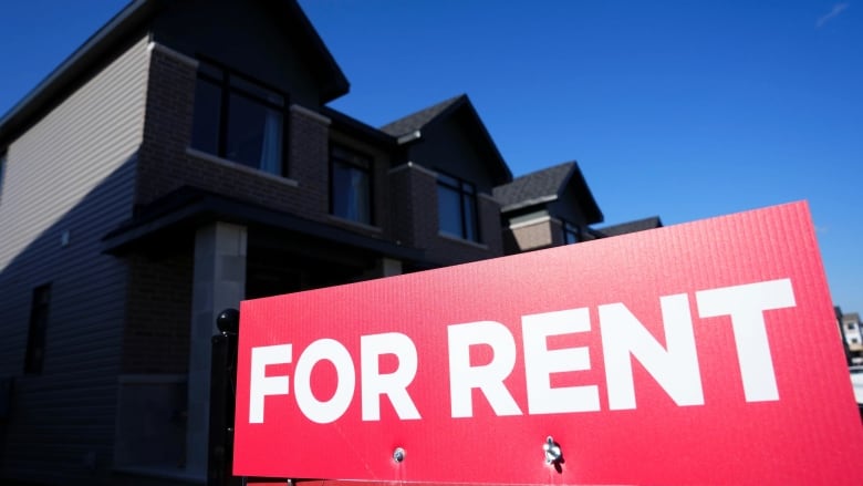 For rent sign with housing development in background.