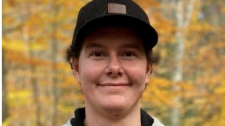 A smiling guy wearing a ball cap and a backpack. 