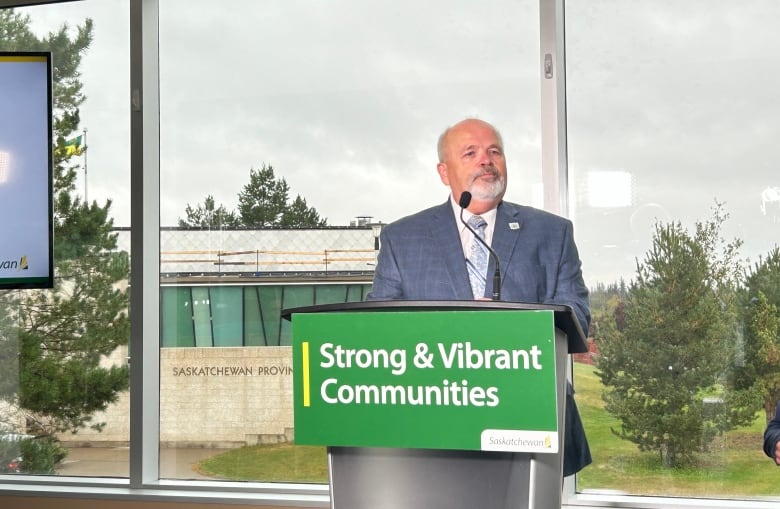 A man stands at a podium speaking into a microphone.