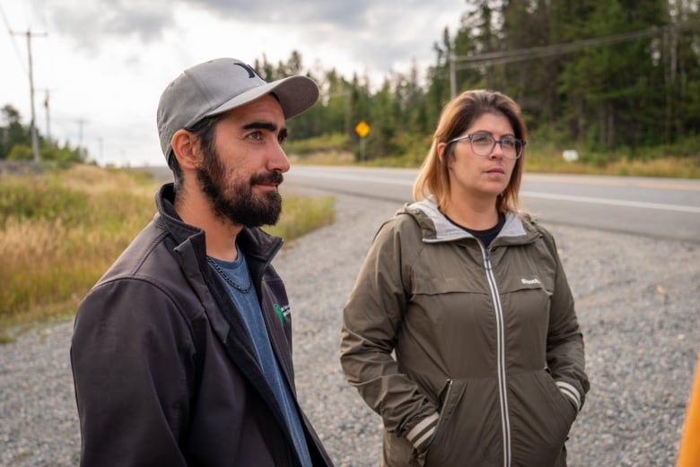 A man and a woman stand on the side of the road 