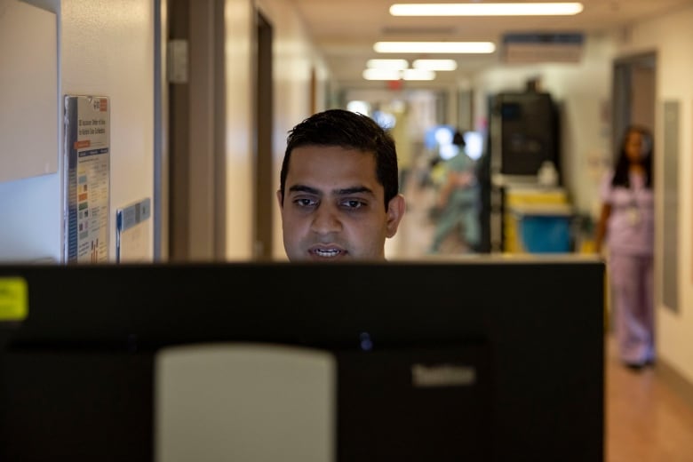 Dr. Amol Verma, a clinician-scientist at St. Michaels Hospital who helped lead the creation and testing of CHARTwatch, stands at a computer.