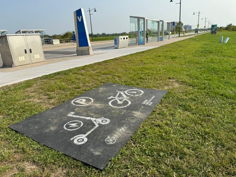 A rubber mat with spray-painted markings of scooters and bicycles. 