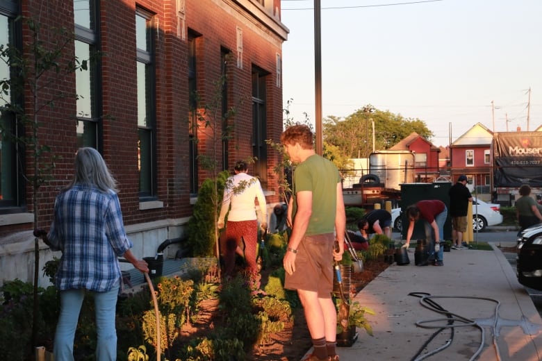 people gardening outside brick building