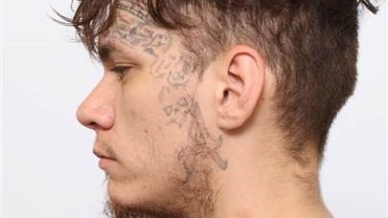 A man's profile with face tattoos and a grey shirt during a mugshot.