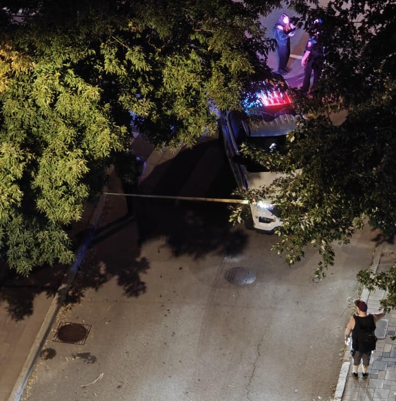 A police vehicle and police tape block a residential street at night.