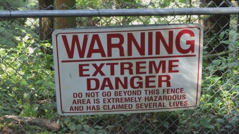 A warning sign on a fence in a mountainous park.