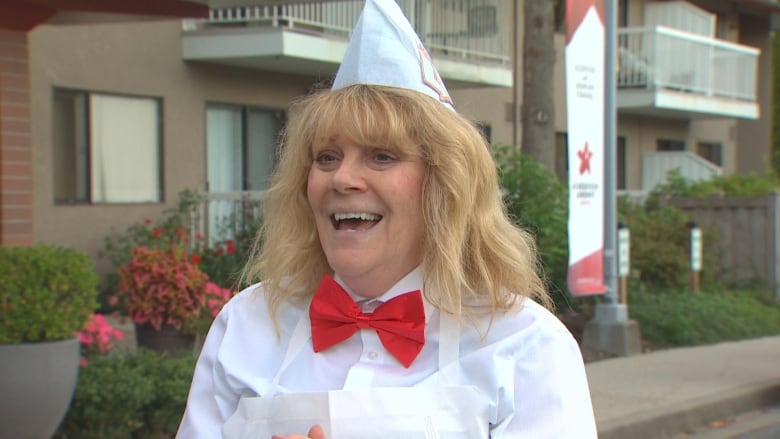 A woman wearing an old-time cinema attendant costume laughs.