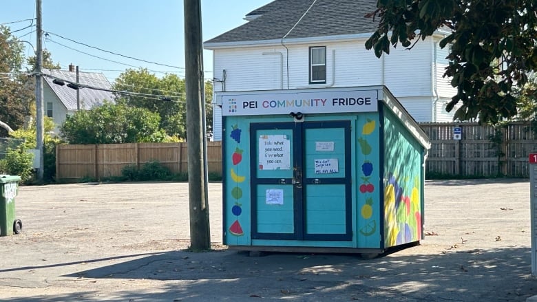 Small, colourful outbuilding used as community fridge.