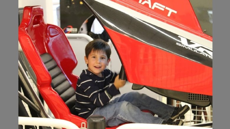 A male child seated in a flight simulator game.