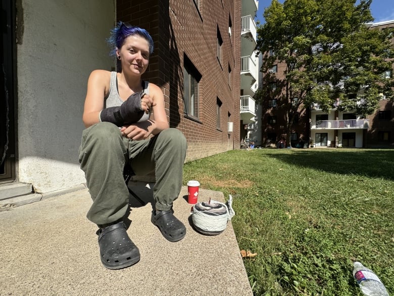 Abby Eplett is sitting on a small stool on her concrete porch.