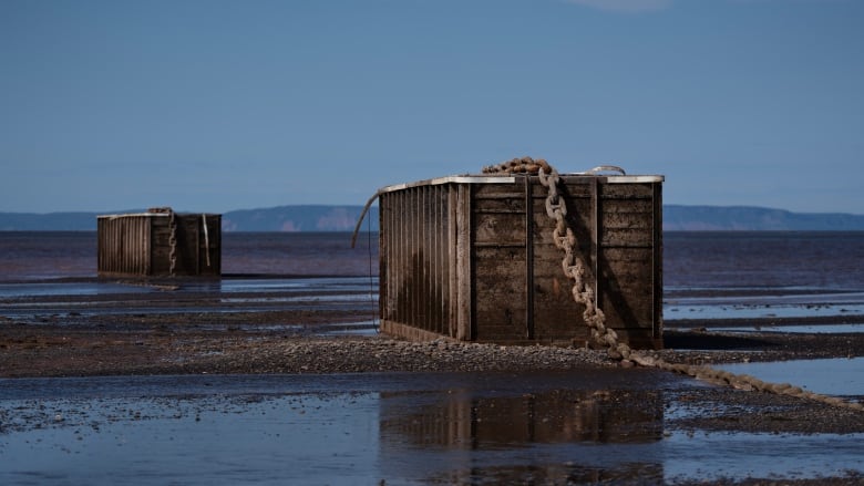 Two crates on a wet surface with a large chain