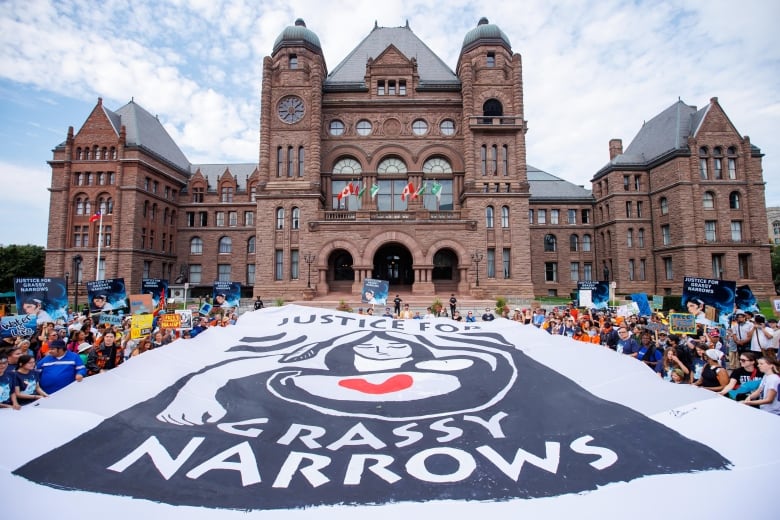 A huge banner is sprawled on the ground in front of a large building.