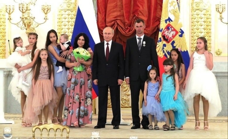 Lilia Syropyatova stands with her husband and their 9 children alongside Russian President Vladimir Putin, who awarded them with the Russian honour of 