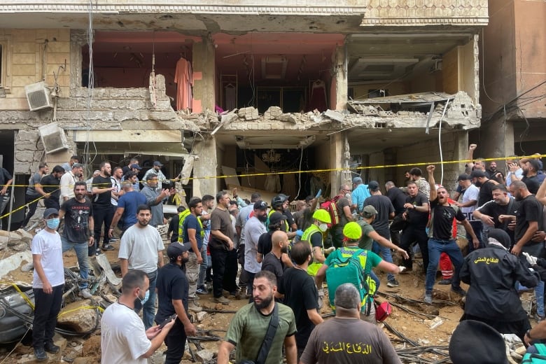 Dozens of people gather near a heavily damaged building at the scene of a missile strike.