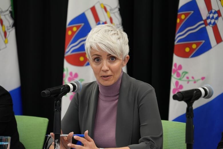 A woman at a table speaks into a microphone.