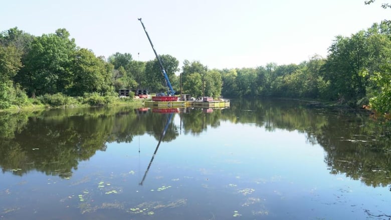 Heavy duty equipment, including some kind of crane, sits on a platform in a lake.