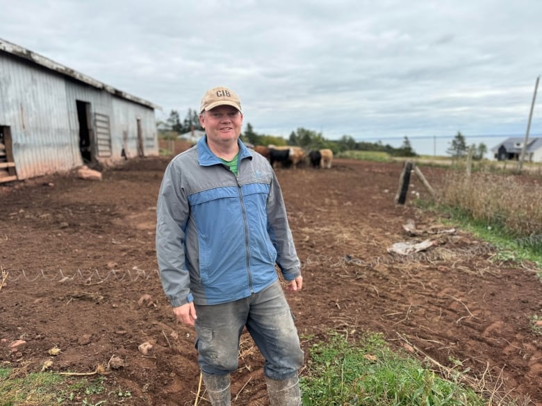 A man stands in front of his a yard of beef cattle 