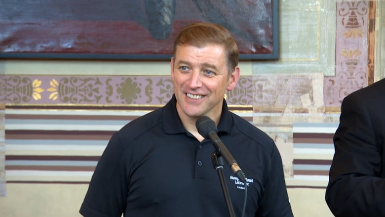 A smiling man wearing a black polo shirt.