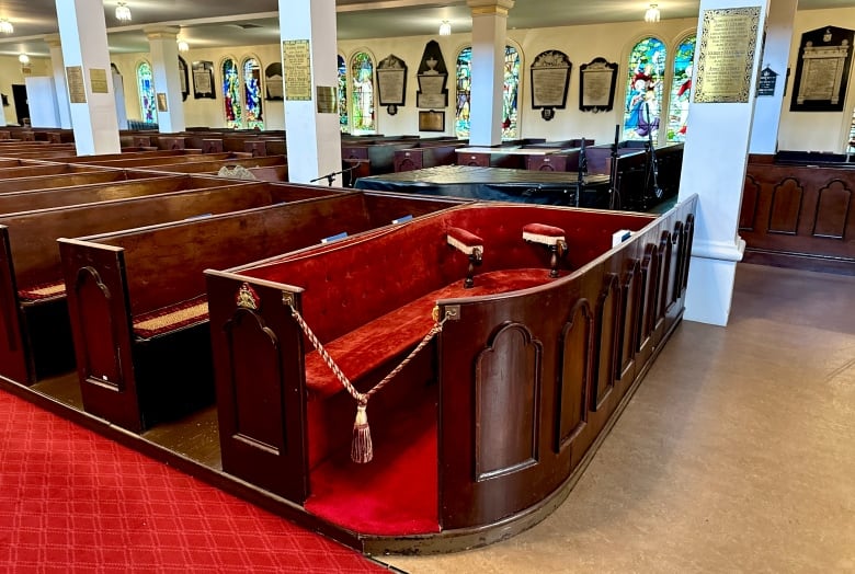 A church pew is shown upholstered with red velvet fabric.