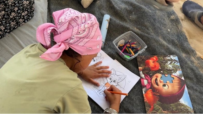 A child colours on a piece of paper.