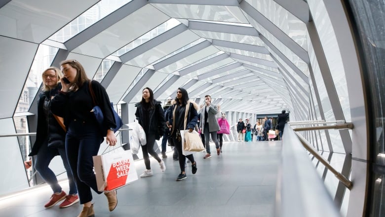 Statistics Canada says the population of the country reached an estimated 41,288,599 on July 1. People walk in an overhead pedestrian crossing in Toronto on Thursday, Dec. 26, 2019.