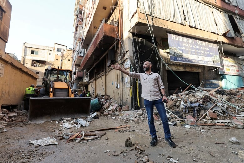 A man holds his arm out after an airstrike hit a city suburb. The man is surrounded by rubble.