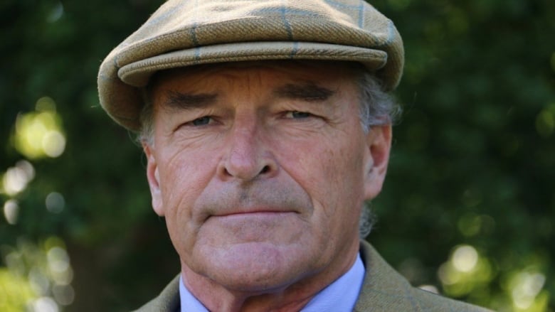 A man wearing a hat is seen in a close-up headshot image 