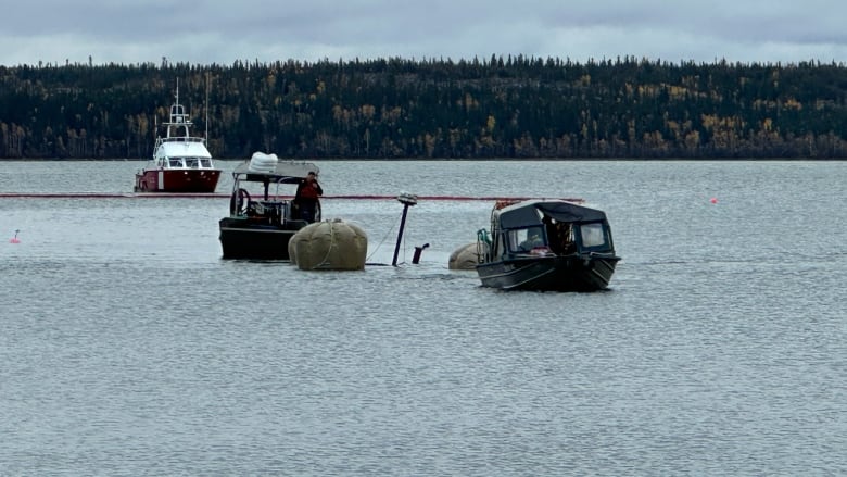 A series of boats on the water, with grey balloons between them.