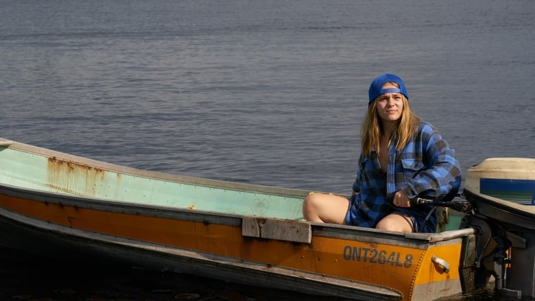 A woman sits in a small boat on a lake. 