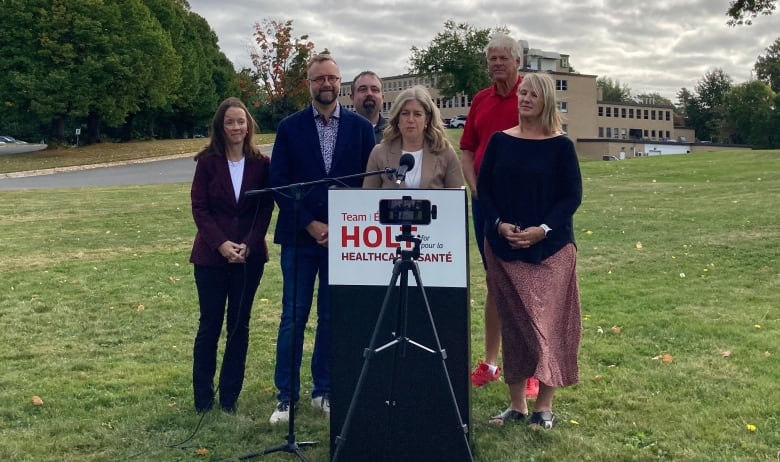 Several people behind a lectern on a lawn