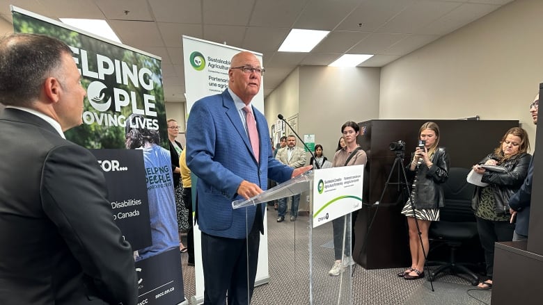 A man in a suit at a podium in an office.