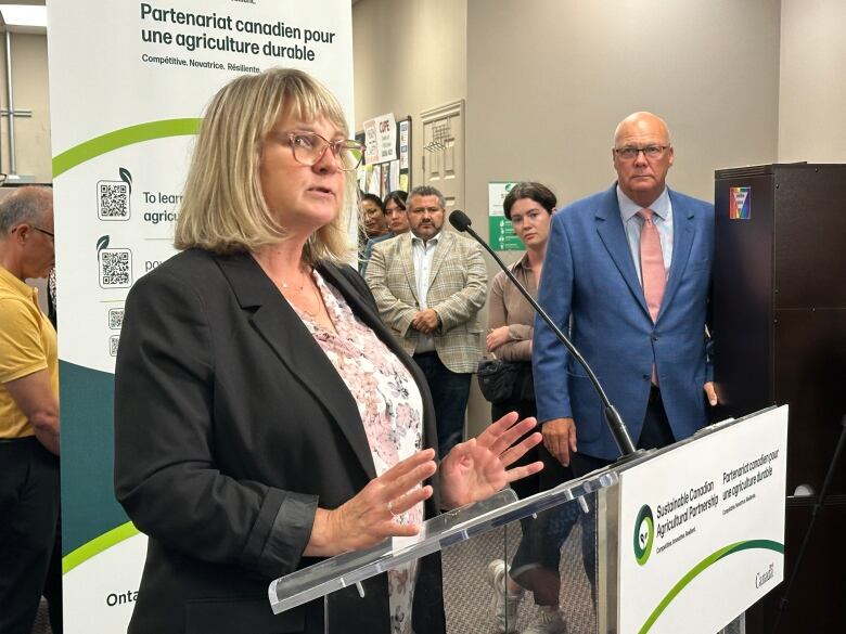 A woman speaks at a podium in an office.