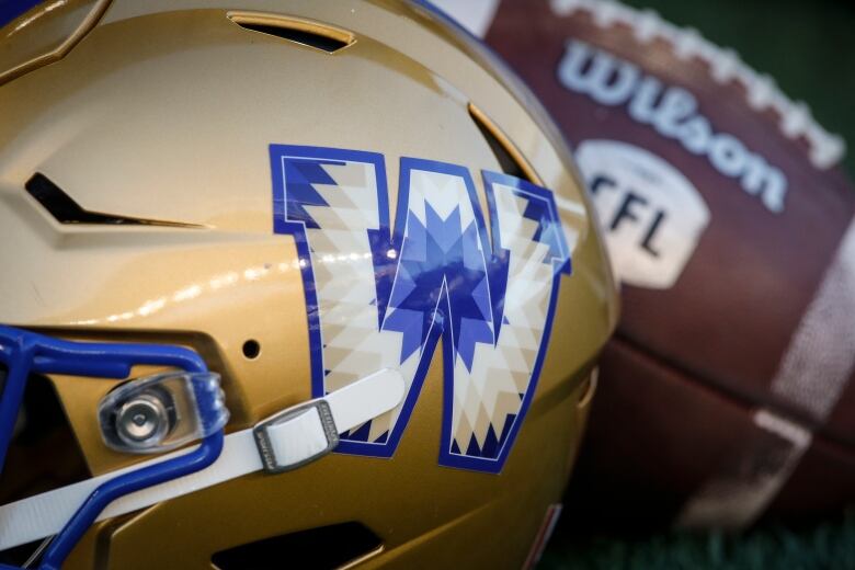 Closeup of a Winnipeg Blue Bombers football helmet in front of a football.