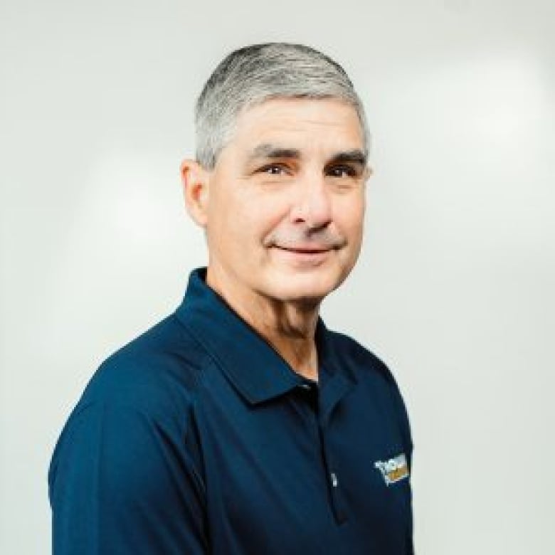 A man with salt and pepper hair is pictured  in a blue polo shirt .