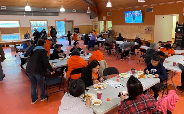 community members eat together, many wearing orange shirts