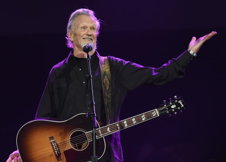 A singer with a guitar gestures while performing.