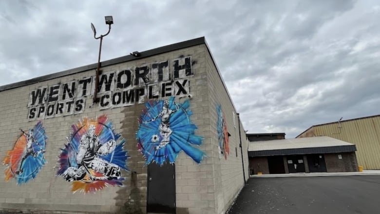 The outside of an area with colourful pictures of people doing sports painted on it.