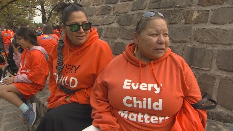 Two women wearing orange hoodies.